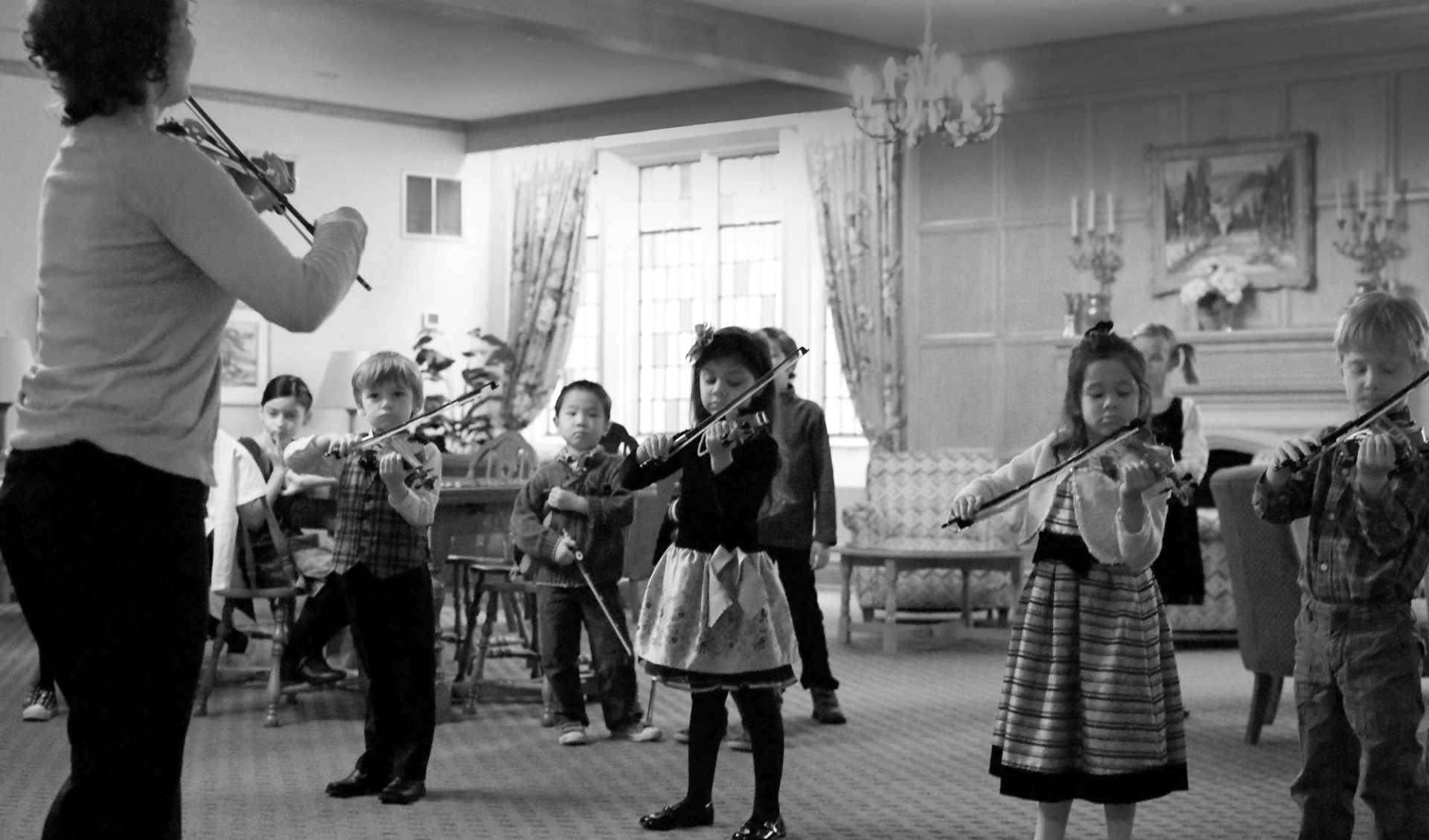 Young group class of students learning to play violin.